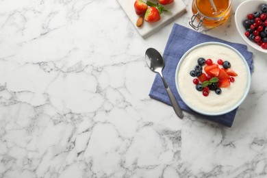 Photo of Delicious semolina pudding with berries on white marble table, flat lay. Space for text