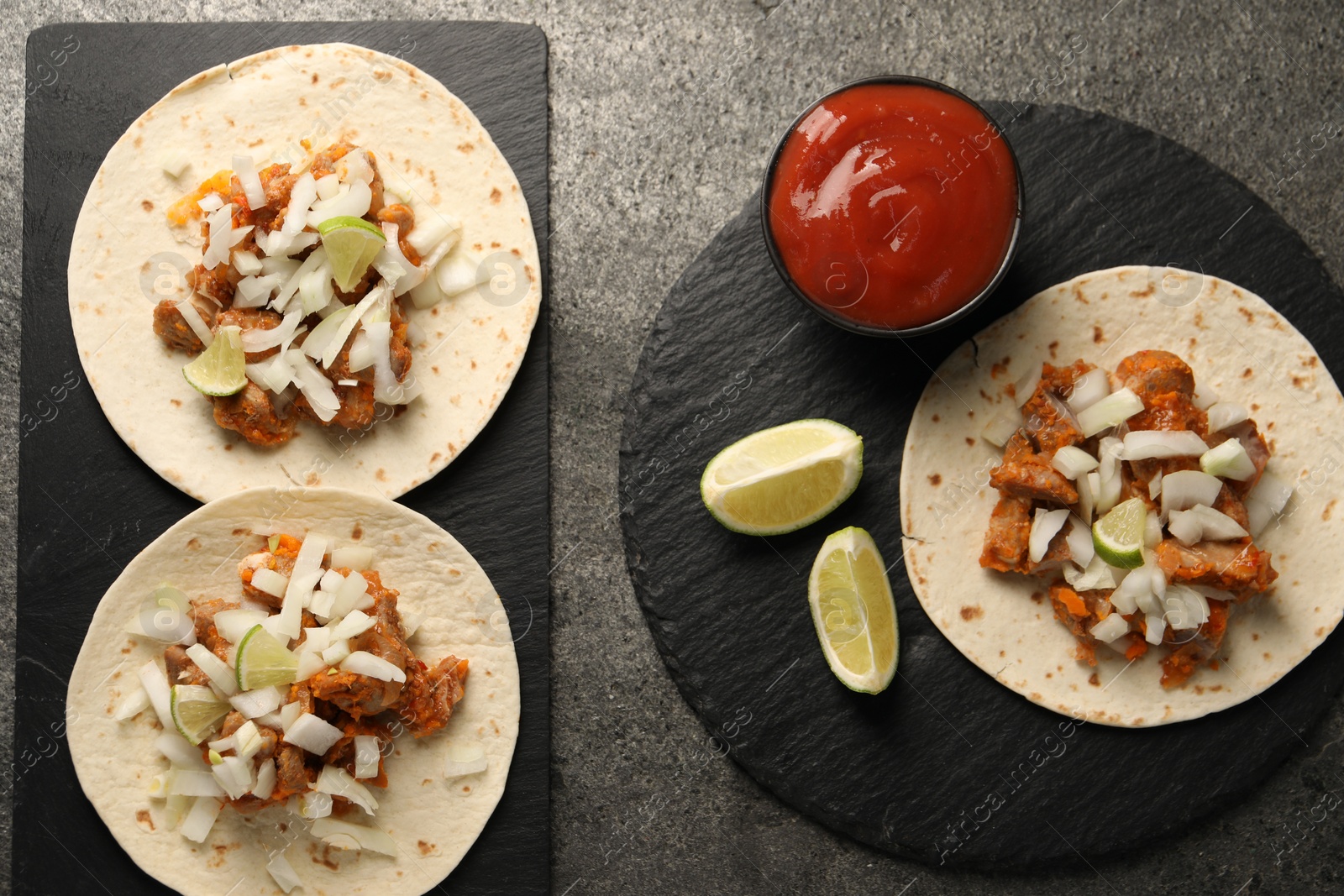 Photo of Delicious tacos with vegetables, meat and ketchup on grey textured table, flat lay