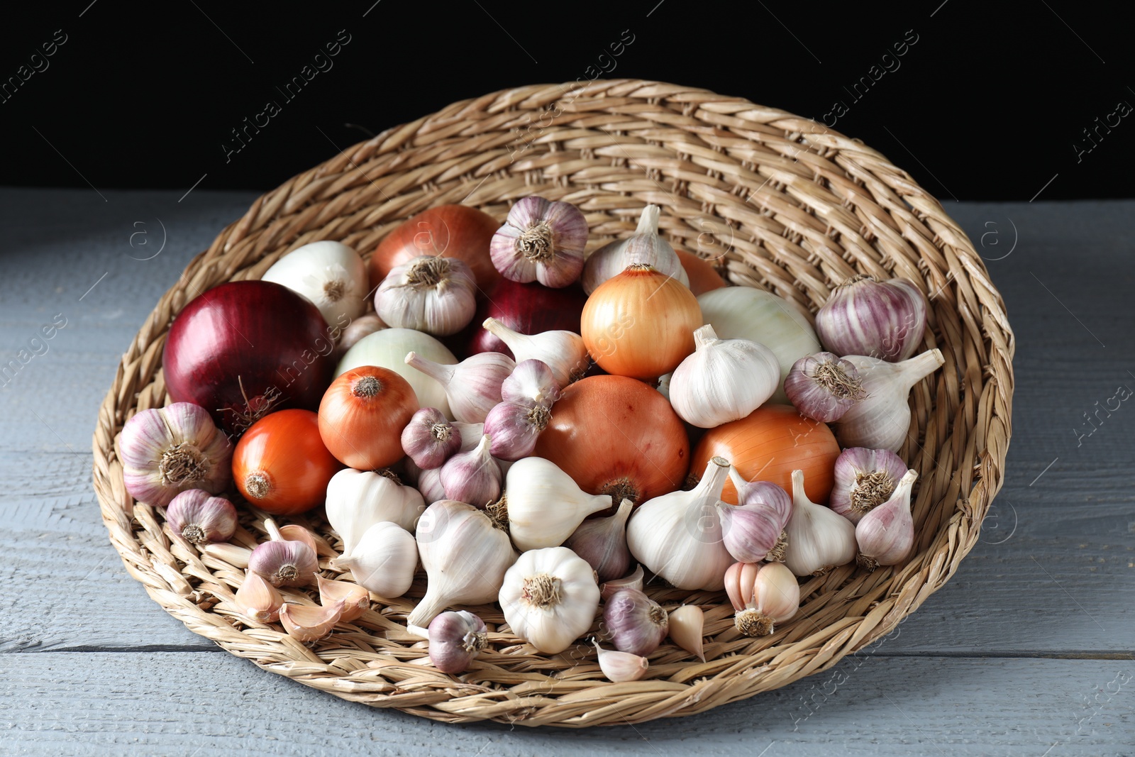 Photo of Fresh raw garlic and onions on gray wooden table