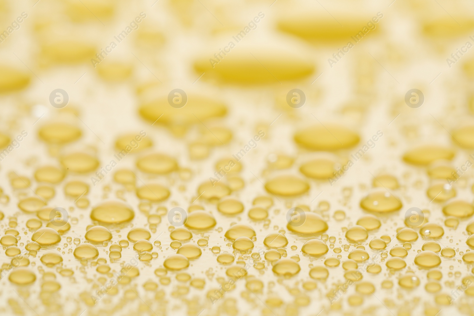 Photo of Water drops on yellow background, closeup view