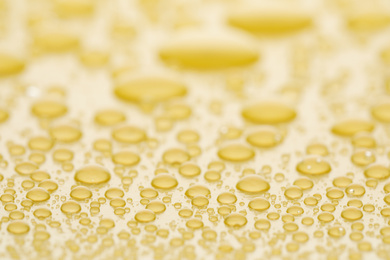 Photo of Water drops on yellow background, closeup view