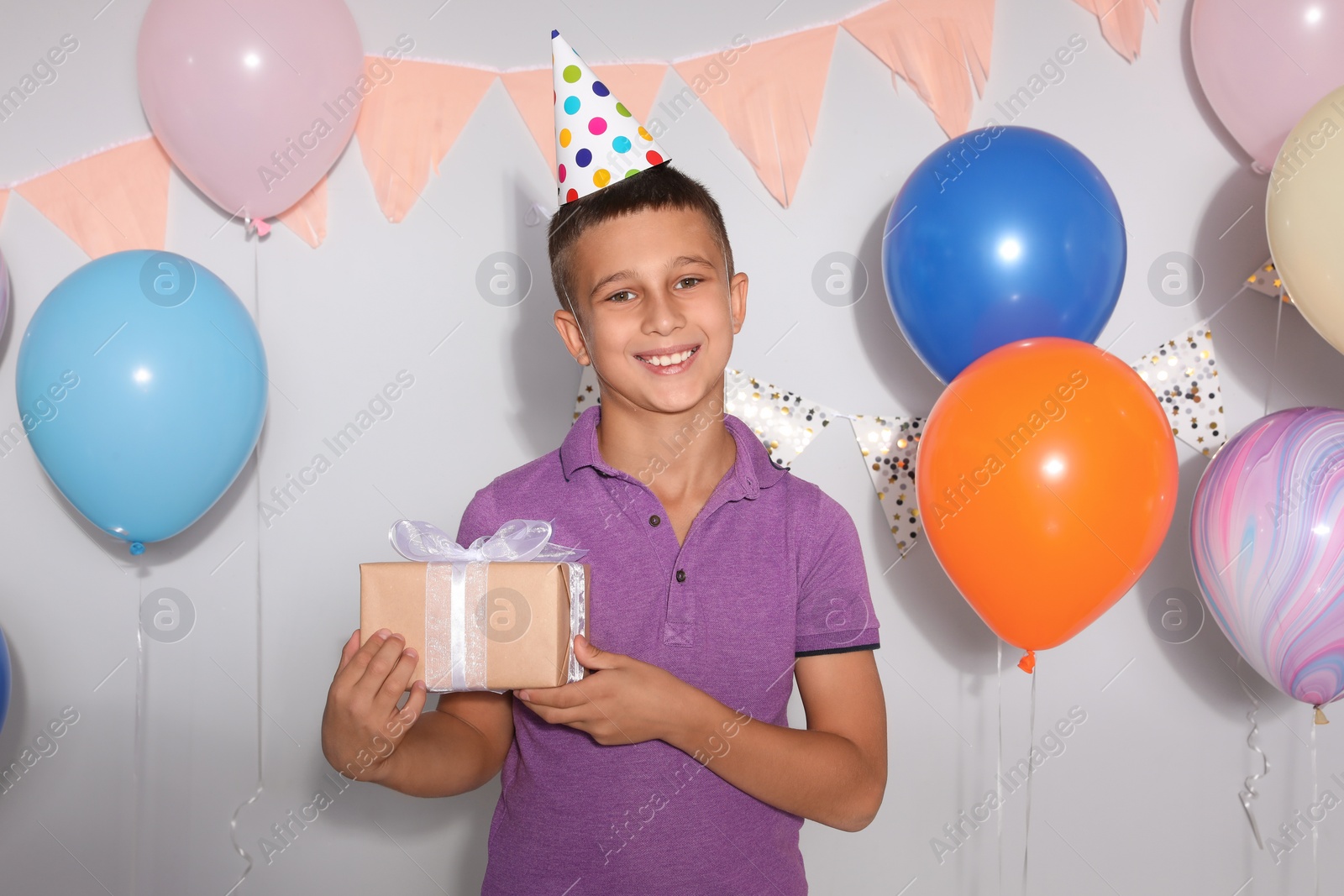 Photo of Happy boy with gift box at birthday party indoors