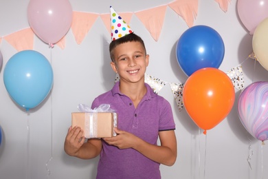 Photo of Happy boy with gift box at birthday party indoors