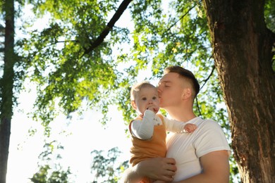 Father with his cute daughter spending time together in park on summer day, space for text