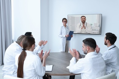 Lecture with online participant. Doctors in meeting room. Using tv for videoconference