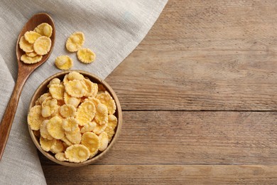 Photo of Bowl and spoon with tasty corn flakes on wooden table, top view. Space for text
