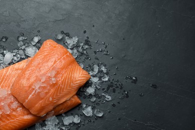 Photo of Fresh raw salmon with ice on black table, flat lay. Space for text