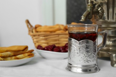 Photo of Traditional Russian samovar, aromatic tea and treats on table indoors