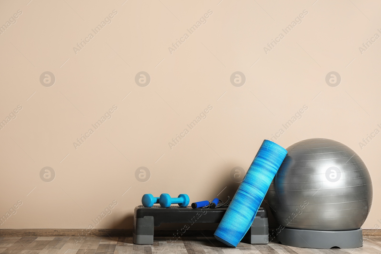 Photo of Set of fitness inventory on floor near color wall. Space for text