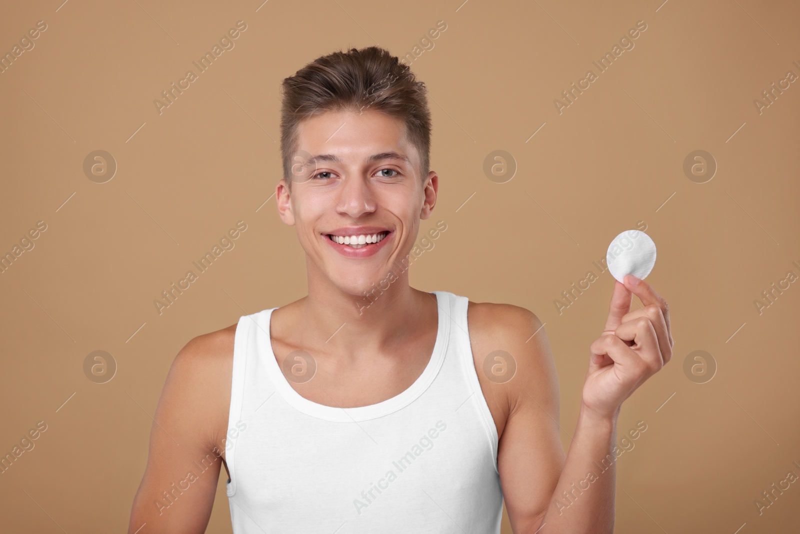 Photo of Handsome man with cotton pad on beige background