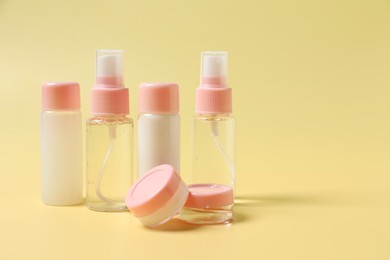 Photo of Cosmetic travel kit. Small containers of personal care products on yellow background, space for text