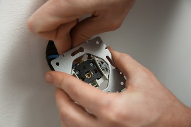 Photo of Professional electrician repairing power socket, closeup view
