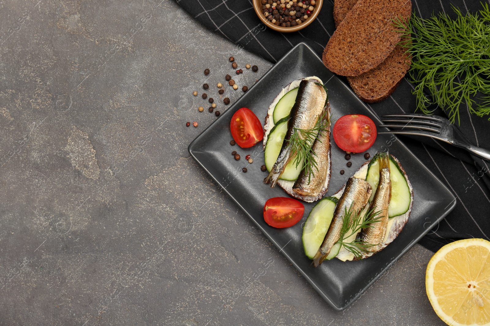 Delicious sandwiches with sprats, cucumber and dill served on grey table, flat lay. Space for text Photo of Delicious sandwiches with sprats, cucumber and dill served on grey table, flat lay. Space for text