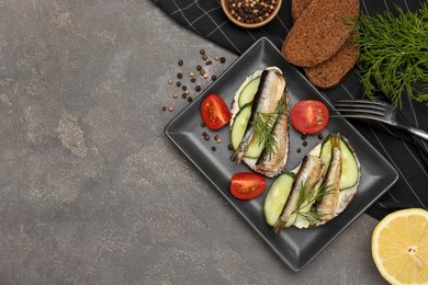 Photo of Delicious sandwiches with sprats, cucumber and dill served on grey table, flat lay. Space for text