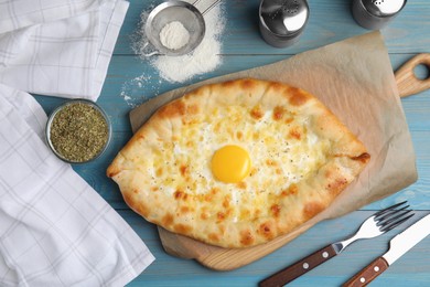 Photo of Fresh homemade khachapuri with cheese and egg served on light blue wooden table, flat lay
