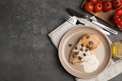 Photo of Delicious chicken fillet with capers and sauce served on grey table, flat lay. Space for text