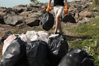 Photo of Man with trash bag full of garbage in nature, closeup. Environmental Pollution concept