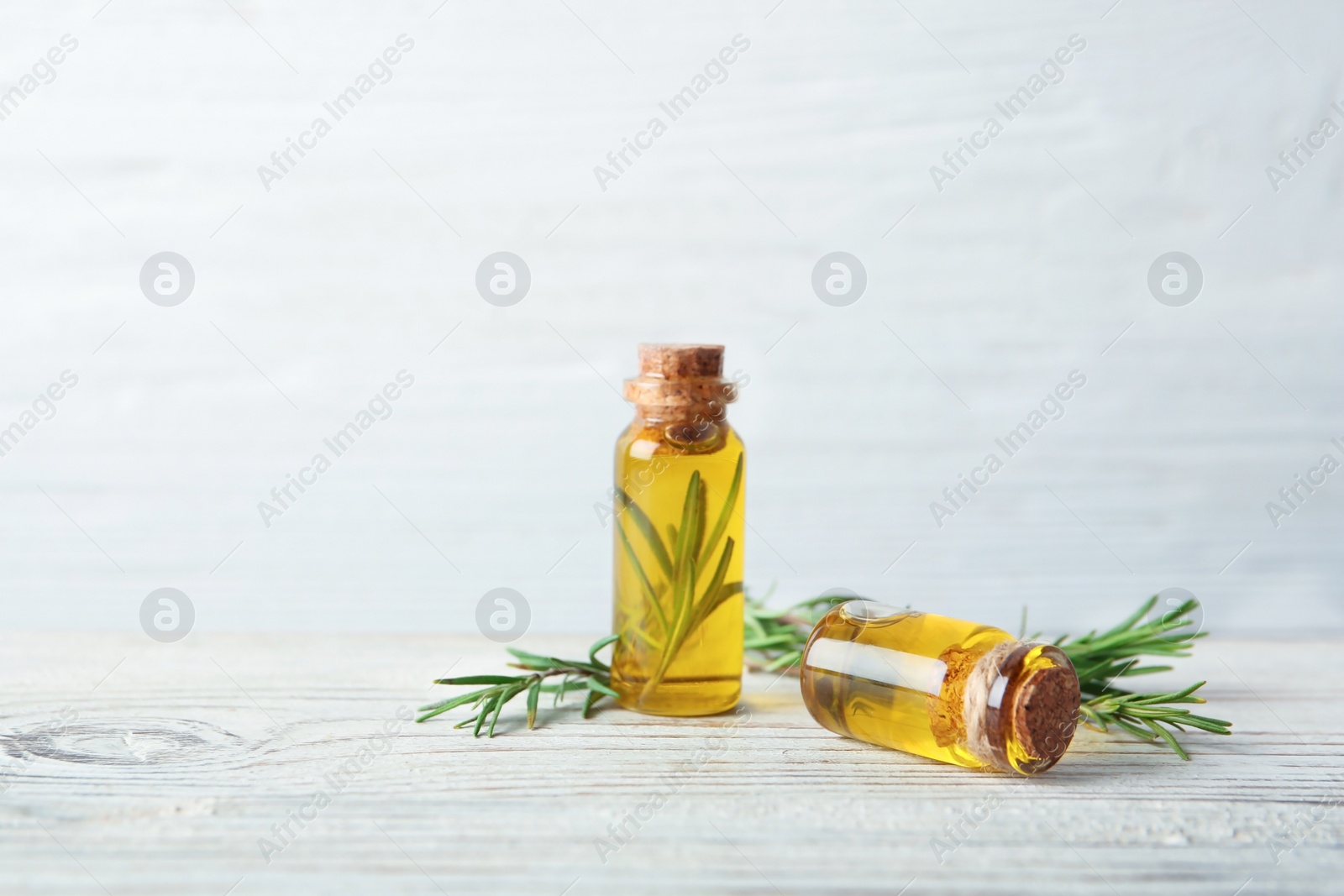 Photo of Bottles with fresh rosemary oil on wooden table