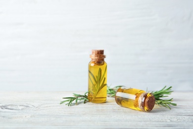 Photo of Bottles with fresh rosemary oil on wooden table