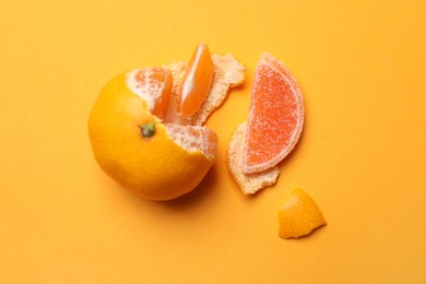 Photo of Fresh tangerine with one jelly candy as its segment on orange background, flat lay. April Fools' Day