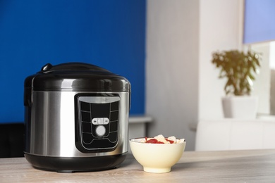 Photo of Modern multi cooker and ingredients on table indoors, space for text