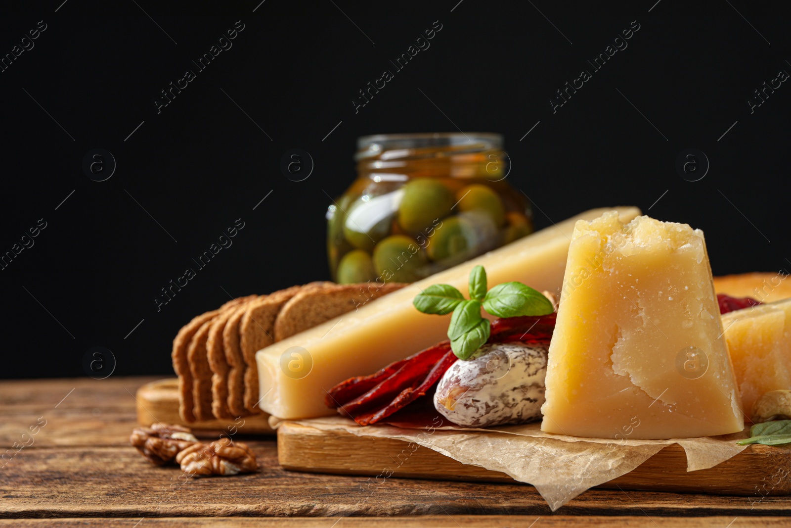Photo of Delicious parmesan cheese, sausage, olives and basil on wooden table