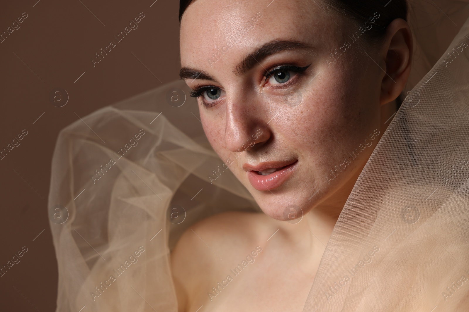 Photo of Fashionable portrait of beautiful woman with fake freckles on brown background, closeup