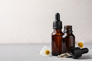 Photo of Composition with bottles of chamomile essential oil on table. Space for text