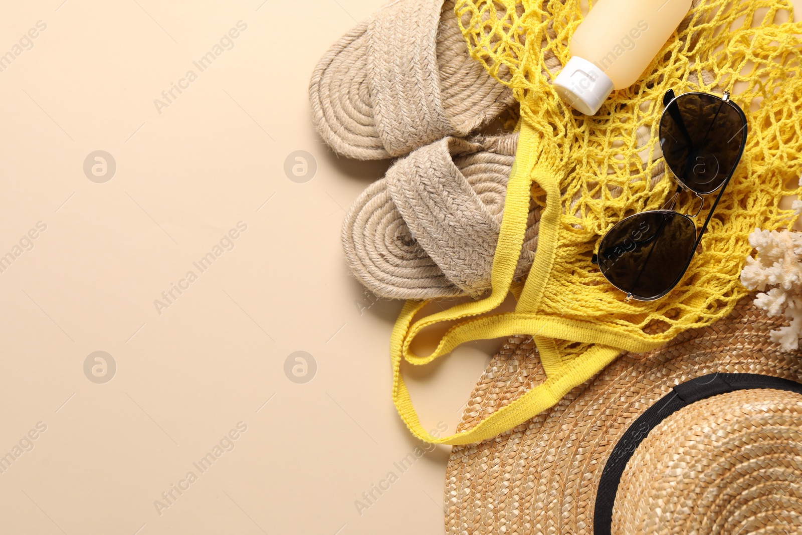 Photo of String bag and different beach accessories on beige background, top view. Space for text