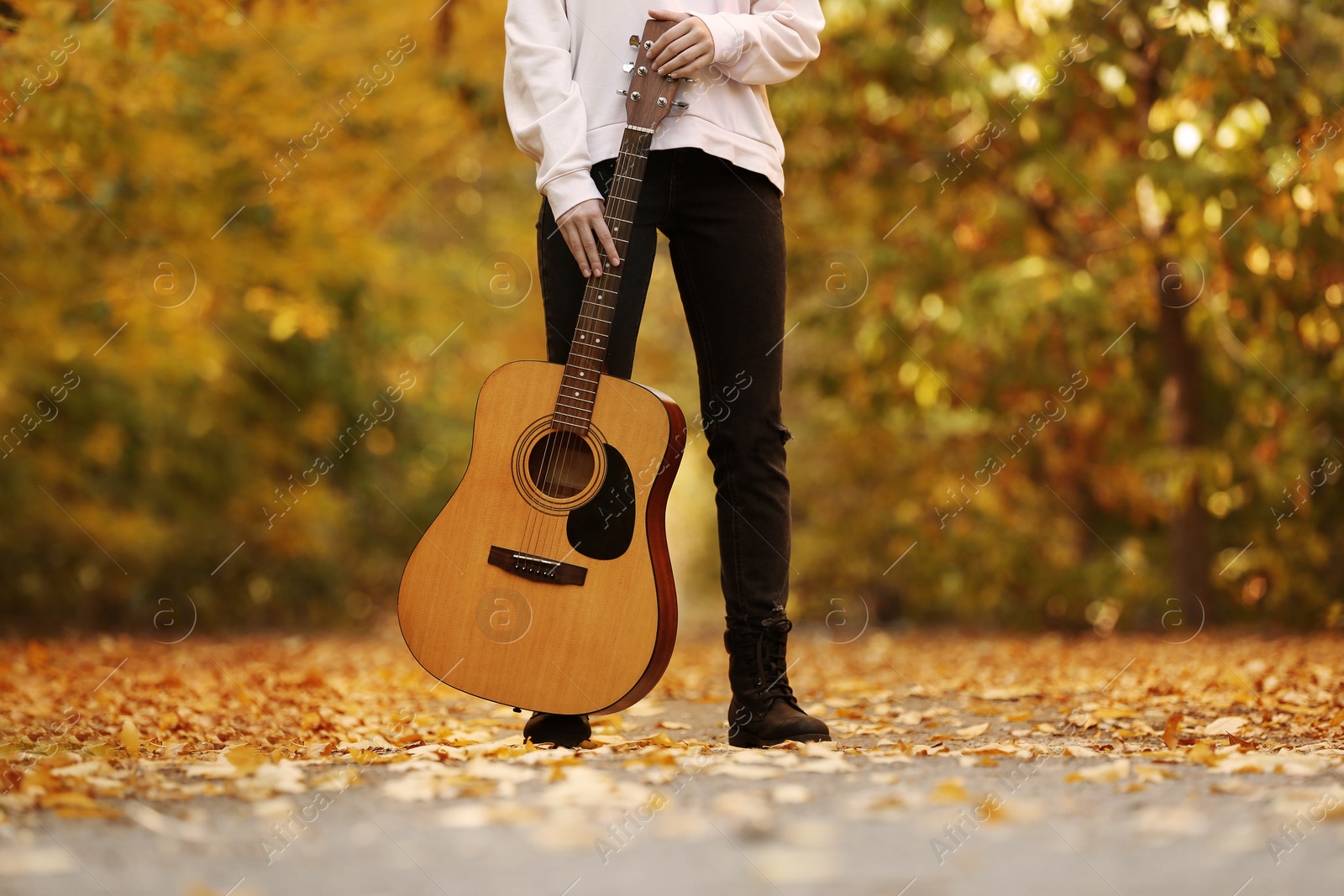 Photo of Teen girl with guitar in autumn park, closeup