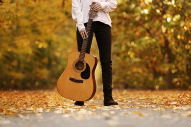 Photo of Teen girl with guitar in autumn park, closeup