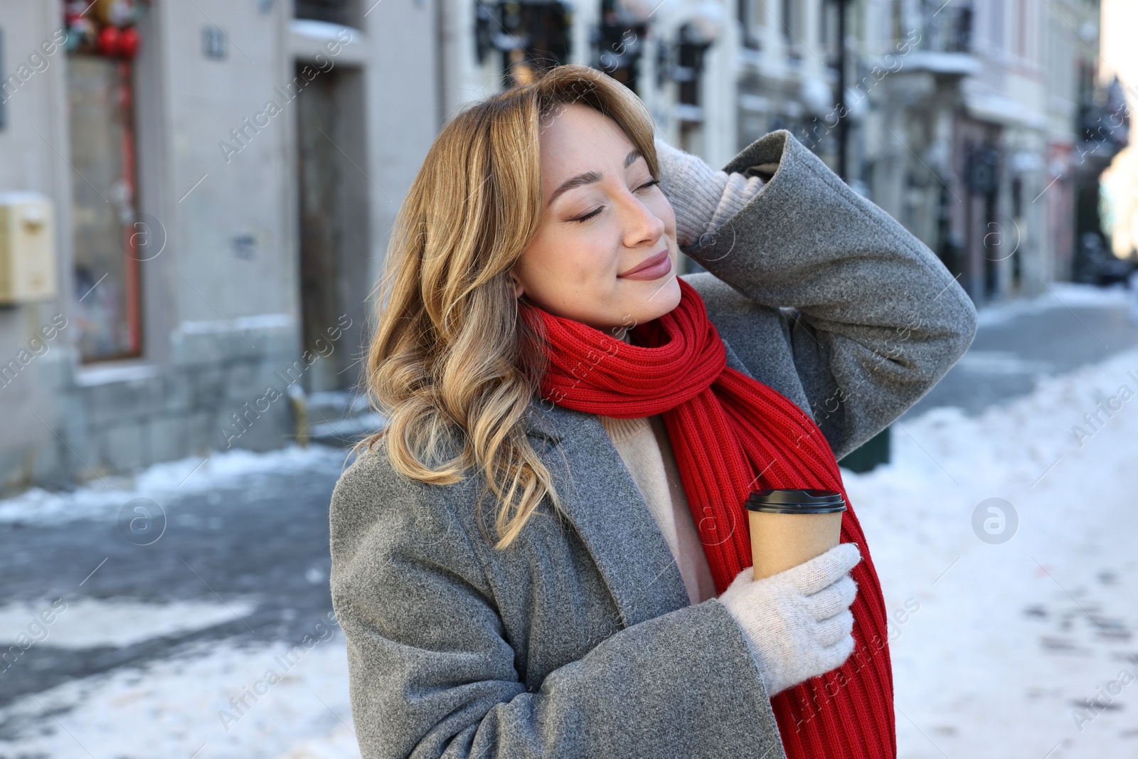 Photo of Portrait of charming woman with paper cup of coffee on city street in winter