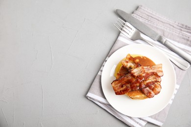 Photo of Delicious pancakes with maple syrup and fried bacon on grey table, flat lay. Space for text