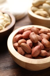 Fresh peanuts in bowl on wooden table, closeup