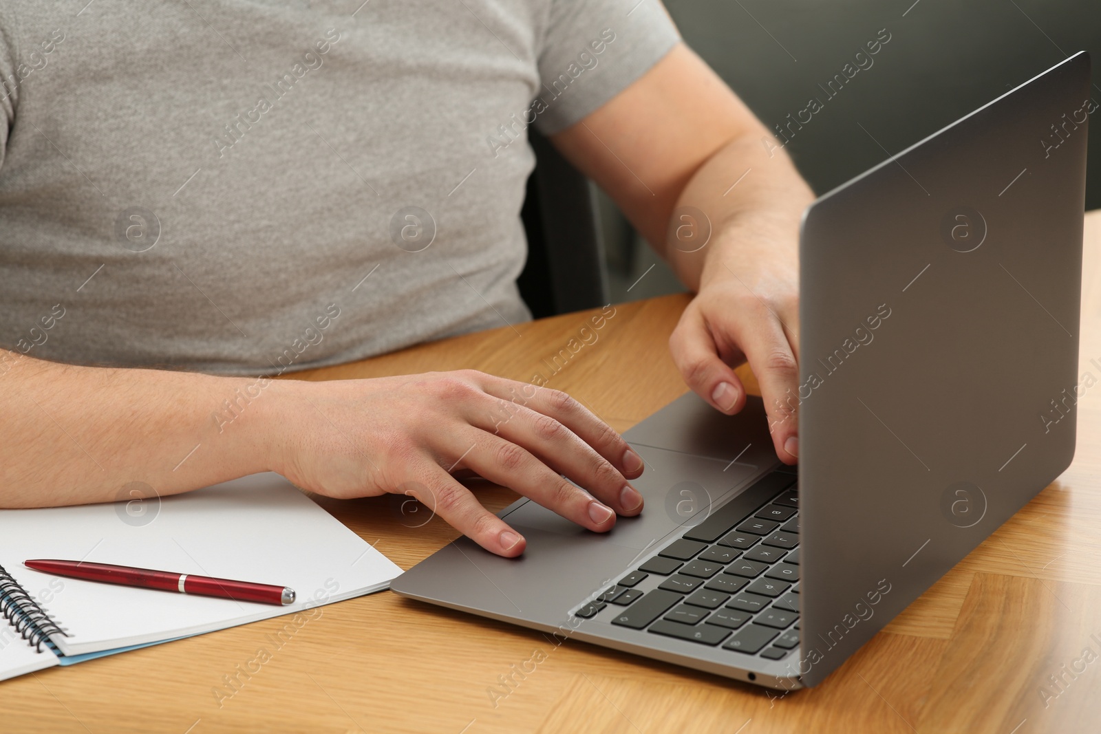 Photo of Man working with laptop at wooden table, closeup