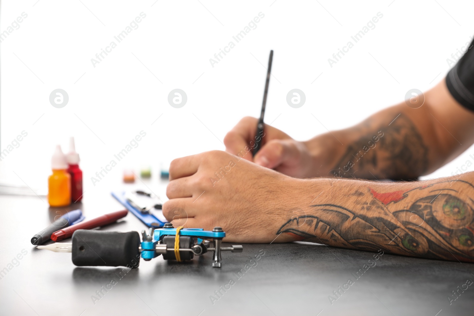 Photo of Professional tattoo artist drawing sketch at table indoors