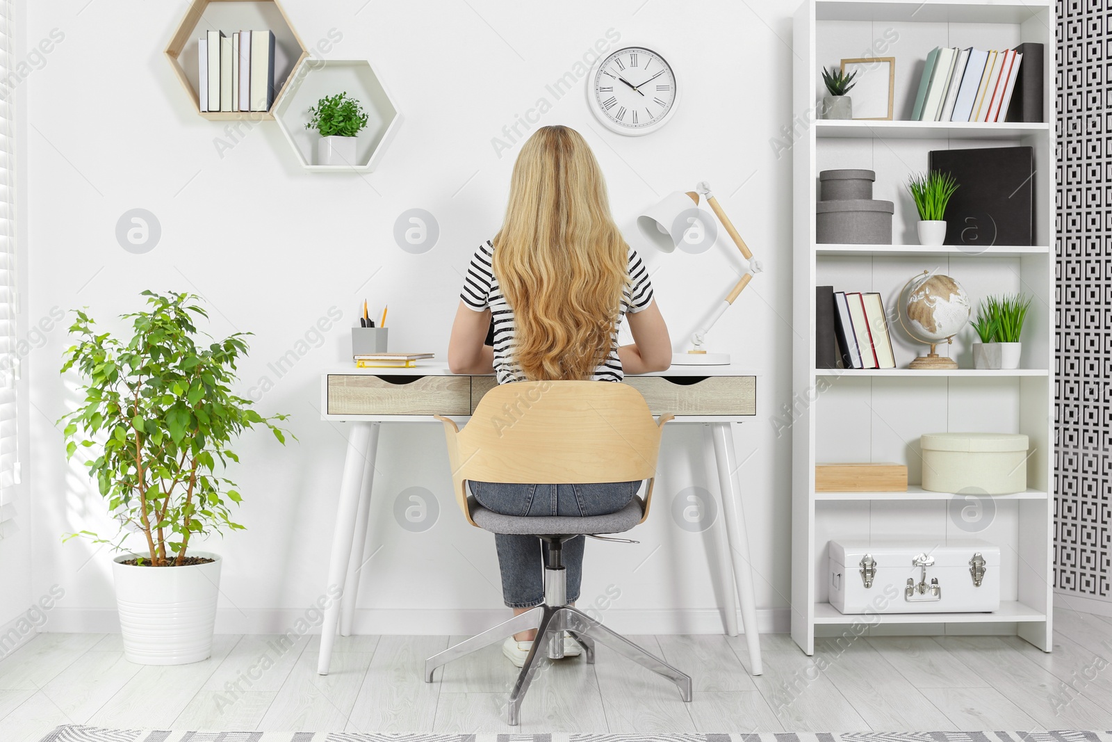 Photo of Home workplace. Woman working at comfortable desk in room, back view