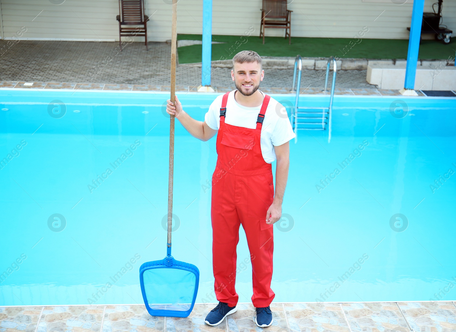 Photo of Male worker cleaning outdoor pool with scoop net