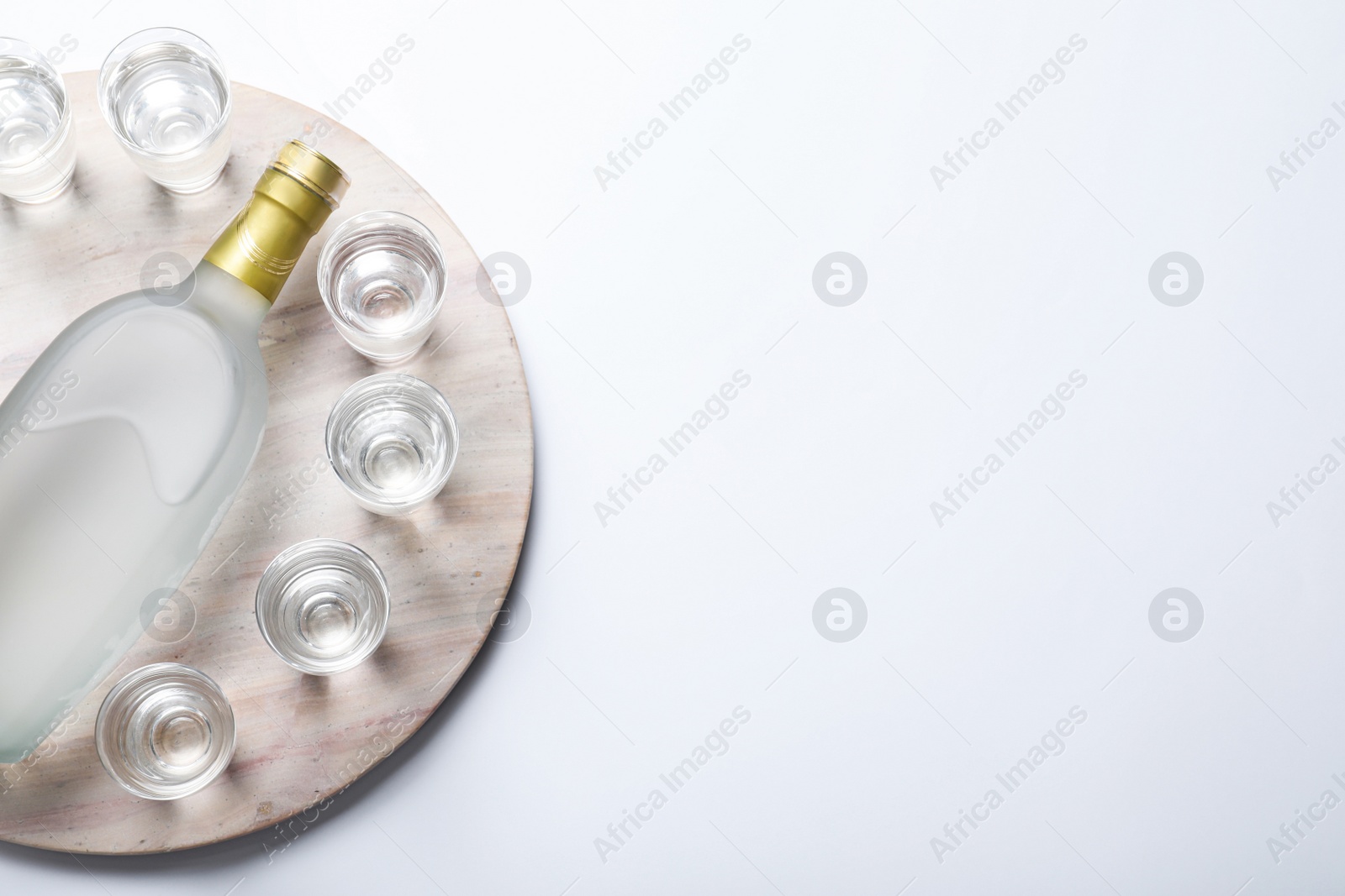 Photo of Bottle of vodka and shot glasses on white background, top view. Space for text