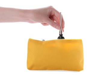Photo of Woman taking out eyeliner from yellow cosmetic bag on white background, closeup