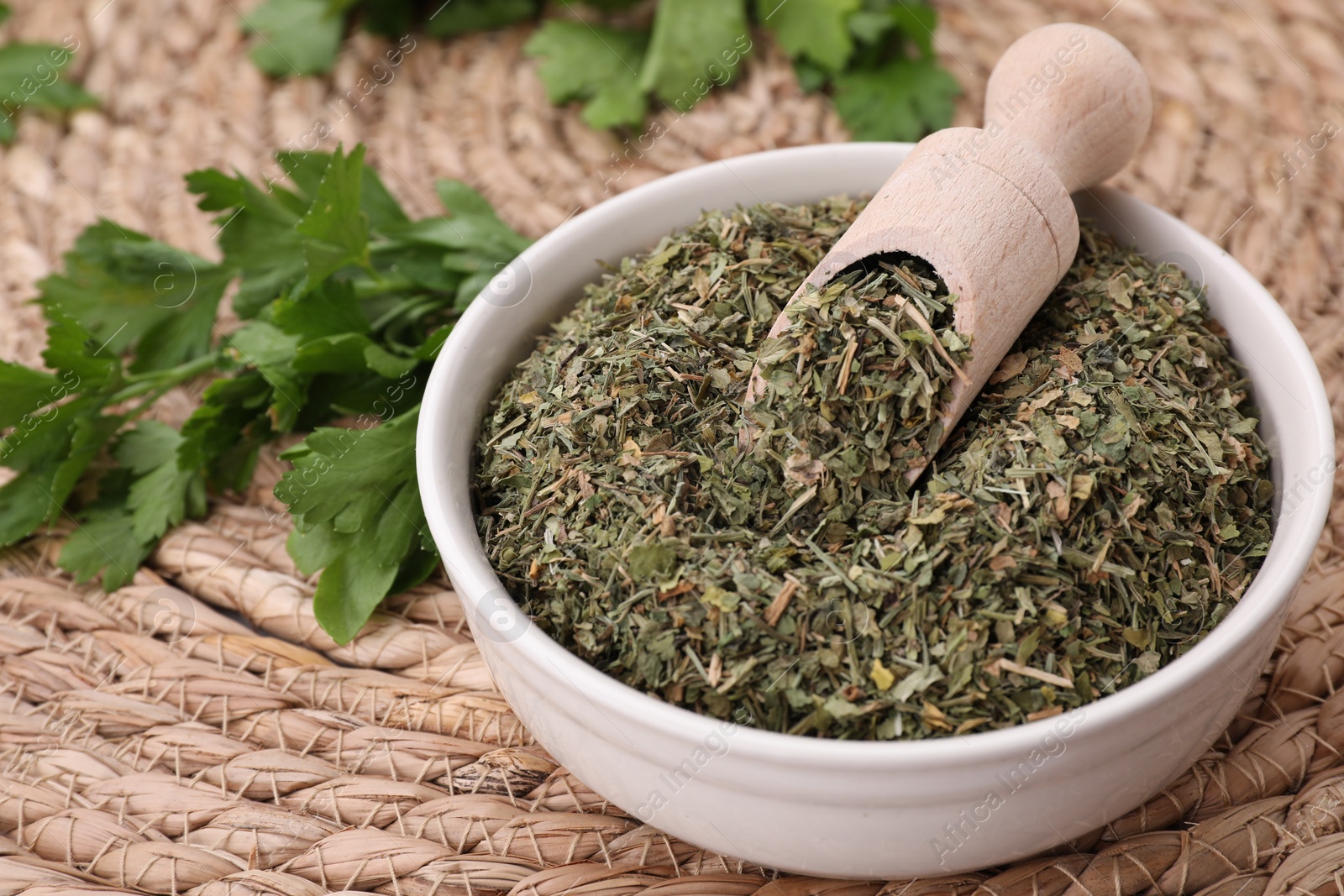 Photo of Dried aromatic parsley and fresh leaves on wicker mat, closeup. Space for text