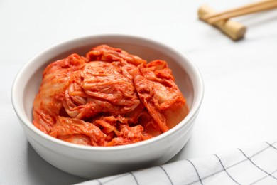 Bowl of spicy cabbage kimchi on white marble table