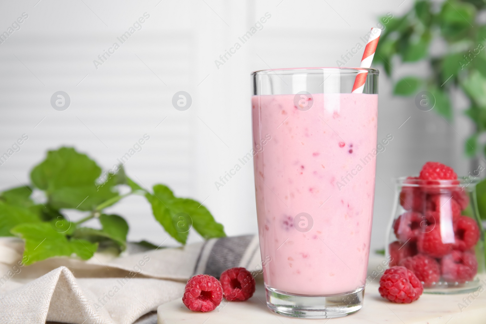 Photo of Glass of tasty raspberry smoothie on light table, space for text