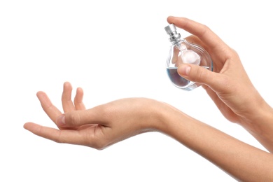 Photo of Young woman spraying perfume onto skin against white background, closeup