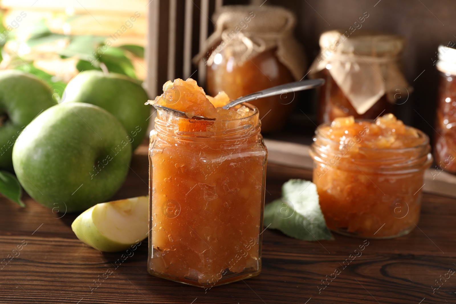 Photo of Delicious apple jam and fresh fruits on wooden table