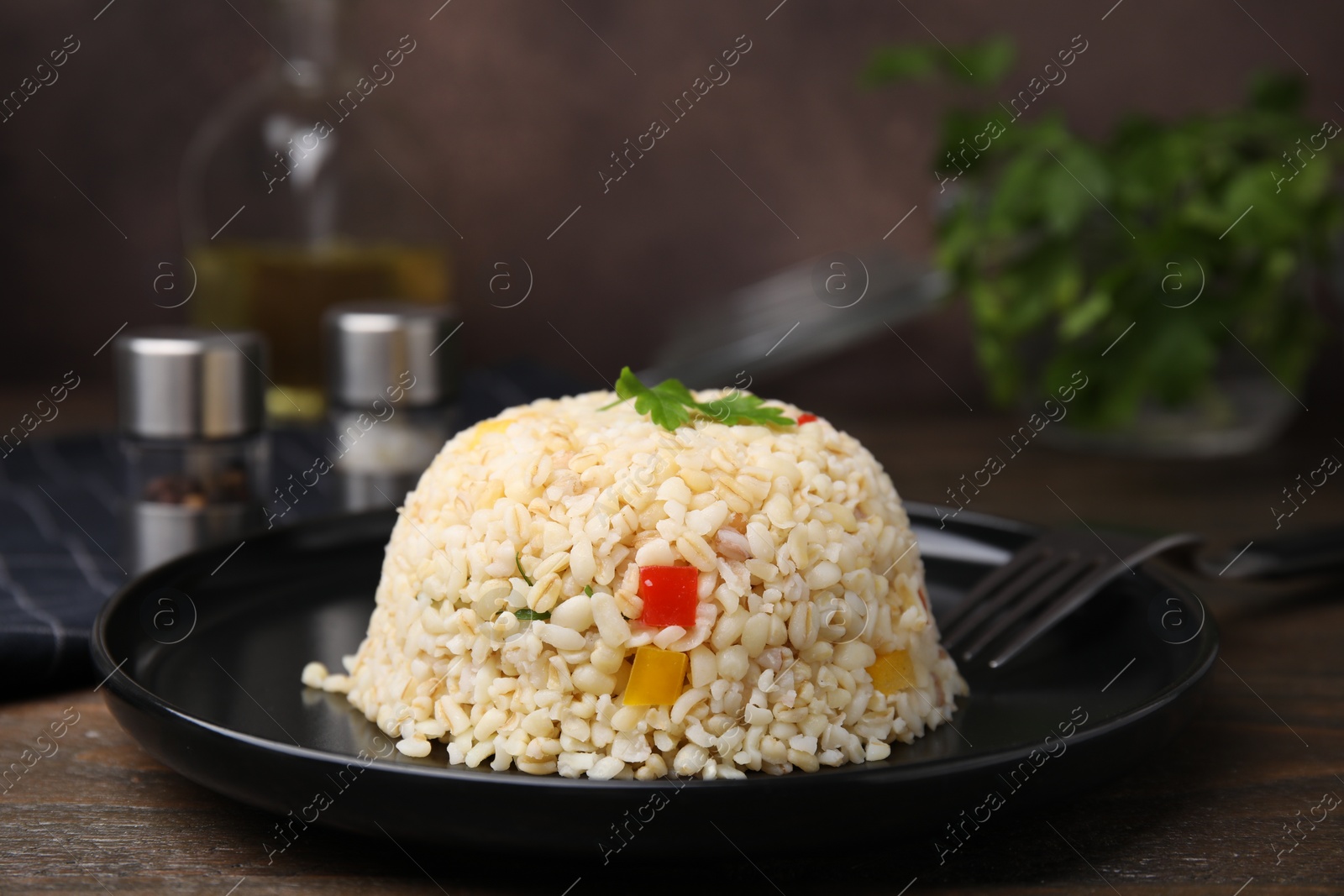 Photo of Delicious bulgur with vegetables and parsley served on wooden table, closeup