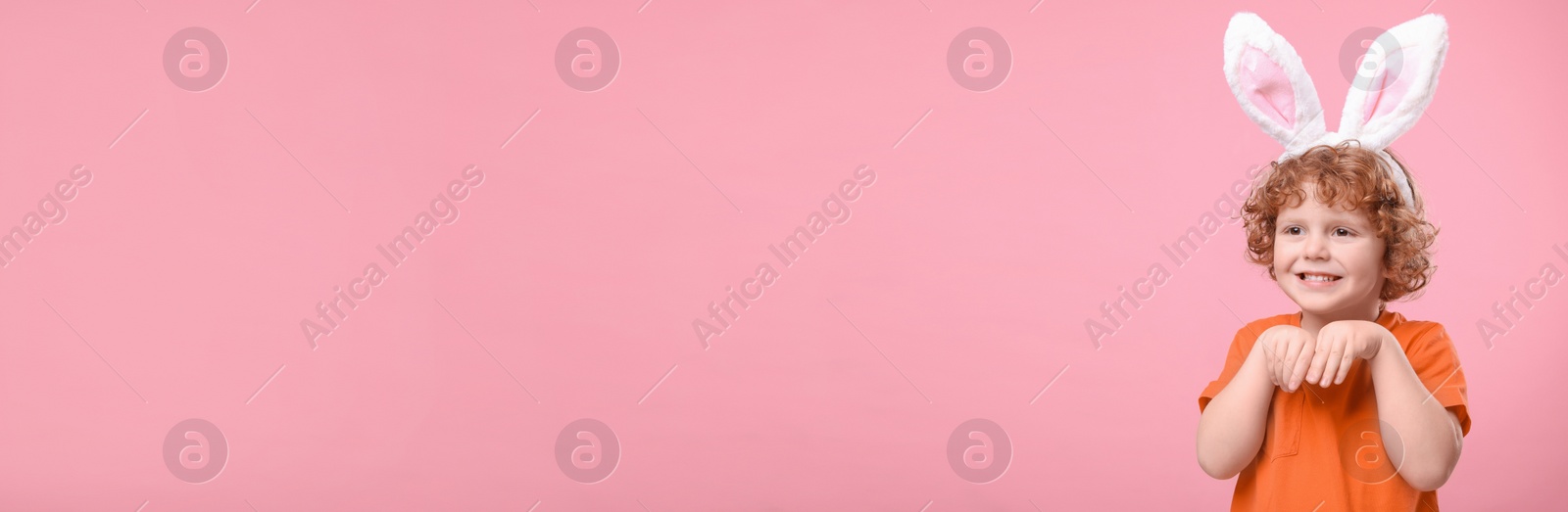 Image of Happy little boy with bunny ears headband on pink background, space for text. Easter celebration. Banner design