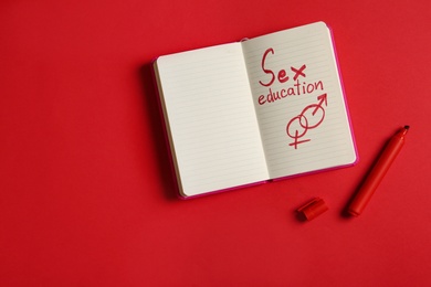 Photo of Notebook with phrase "SEX EDUCATION" on red background, flat lay. Space for text