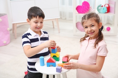 Photo of Cute children playing with colorful blocks at home