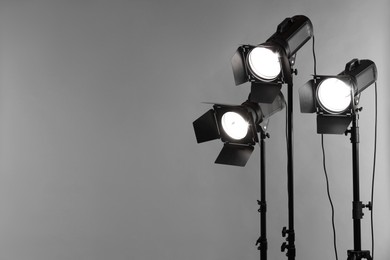 Grey photo background and professional lighting equipment in studio. Space for text